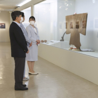 The emperor, empress and their daughter Princess Aiko view the clothing worn by the imperial couple at the 2019 Ceremony of Accession at an exhibition celebrating their wedding anniversary and the emperor’s accession anniversary in Tokyo on May 30. | KYODO