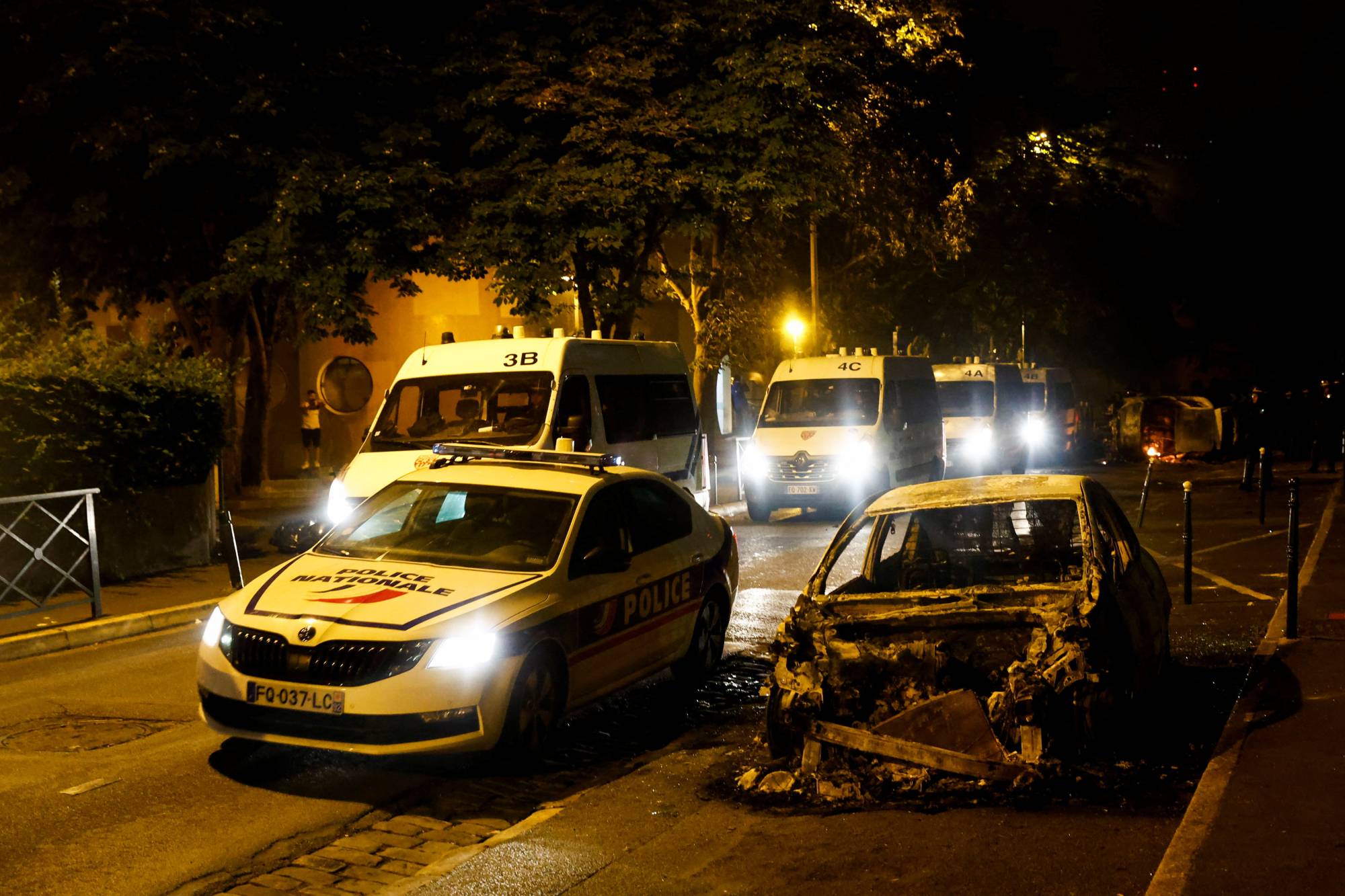 سيارة محترقة بجوار سيارة للشرطة في نانتير ، إحدى ضواحي باريس ، يوم الجمعة. | رويترز