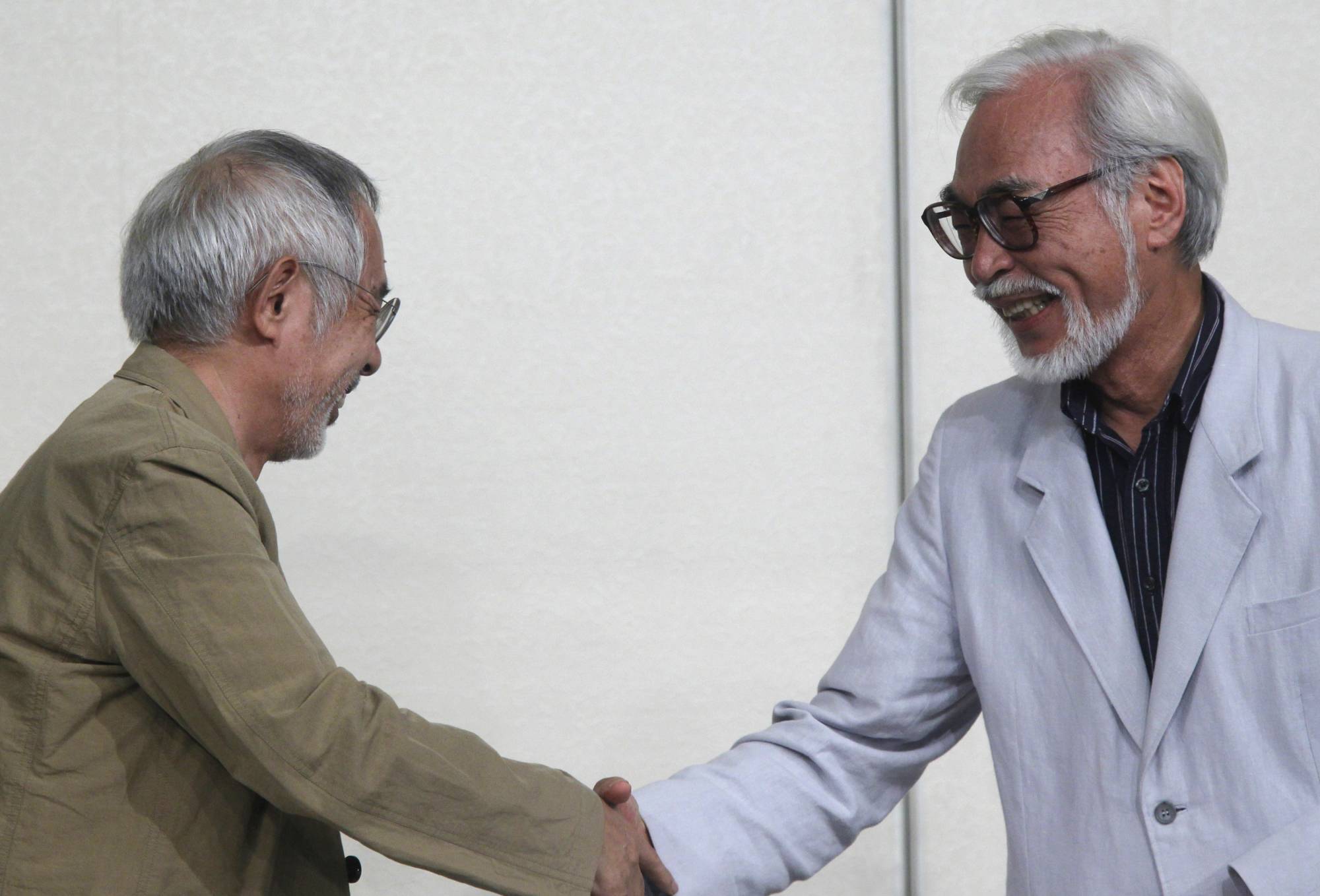 Japanese director Hayao Miyazaki (right) shakes hands with Studio Ghibli Chairman and Producer Toshio Suzuki during a news conference held to announce his retirement from film in 2013. | REUTERS
