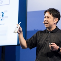 FARM8 CEO Kabasawa talking with a bottle of sake from his pocket during his pitch.