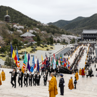 A children’s procession featuring the flags of the 51 member countries of the Buddhist Summit makes the approach to the main hall of the Royal Grand Hall of Buddhism at Muryojuji Head Temple in Kato, Hyogo Prefecture, on April 8. | THE BUDDHIST SUMMIT HEADQUARTERS