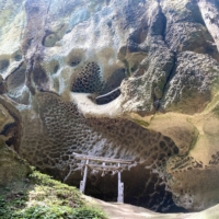 A torii gate is placed in a location where massive boulders and rocks, made of white tuff with honeycomb-like holes, are intricately arranged.